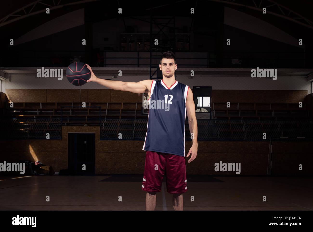 Un jeune homme adulte, le basket-ball player holding ball dans une main, à l'intérieur Banque D'Images