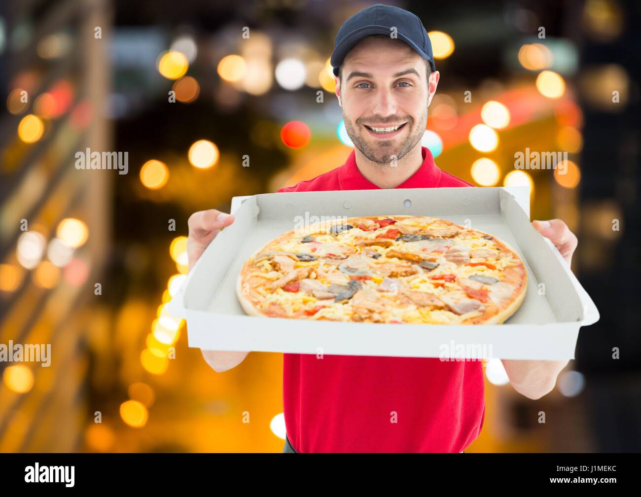 Digital composite de Happy livreur montrant la pizza dans la ville la nuit. Lights Banque D'Images