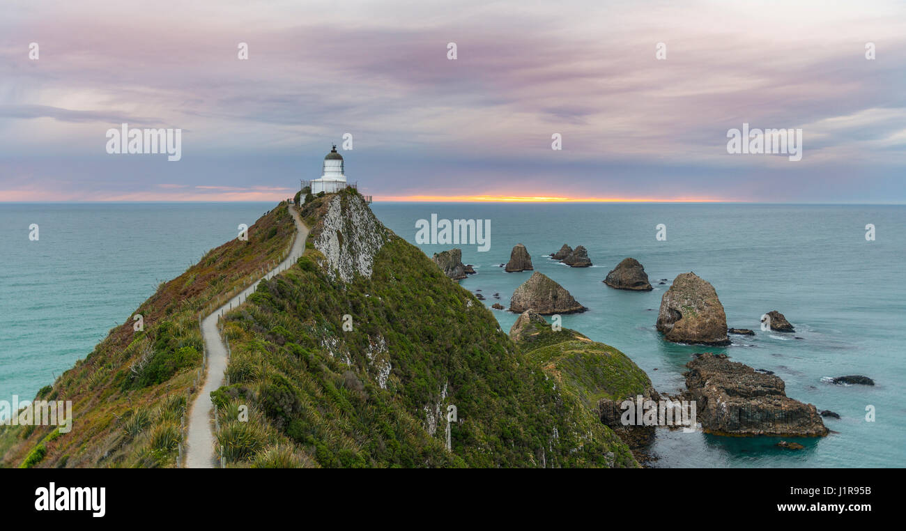 Le lever du soleil, au phare, le Nugget Point, Catlins, Région de l'Otago Southland, Nouvelle-Zélande Banque D'Images