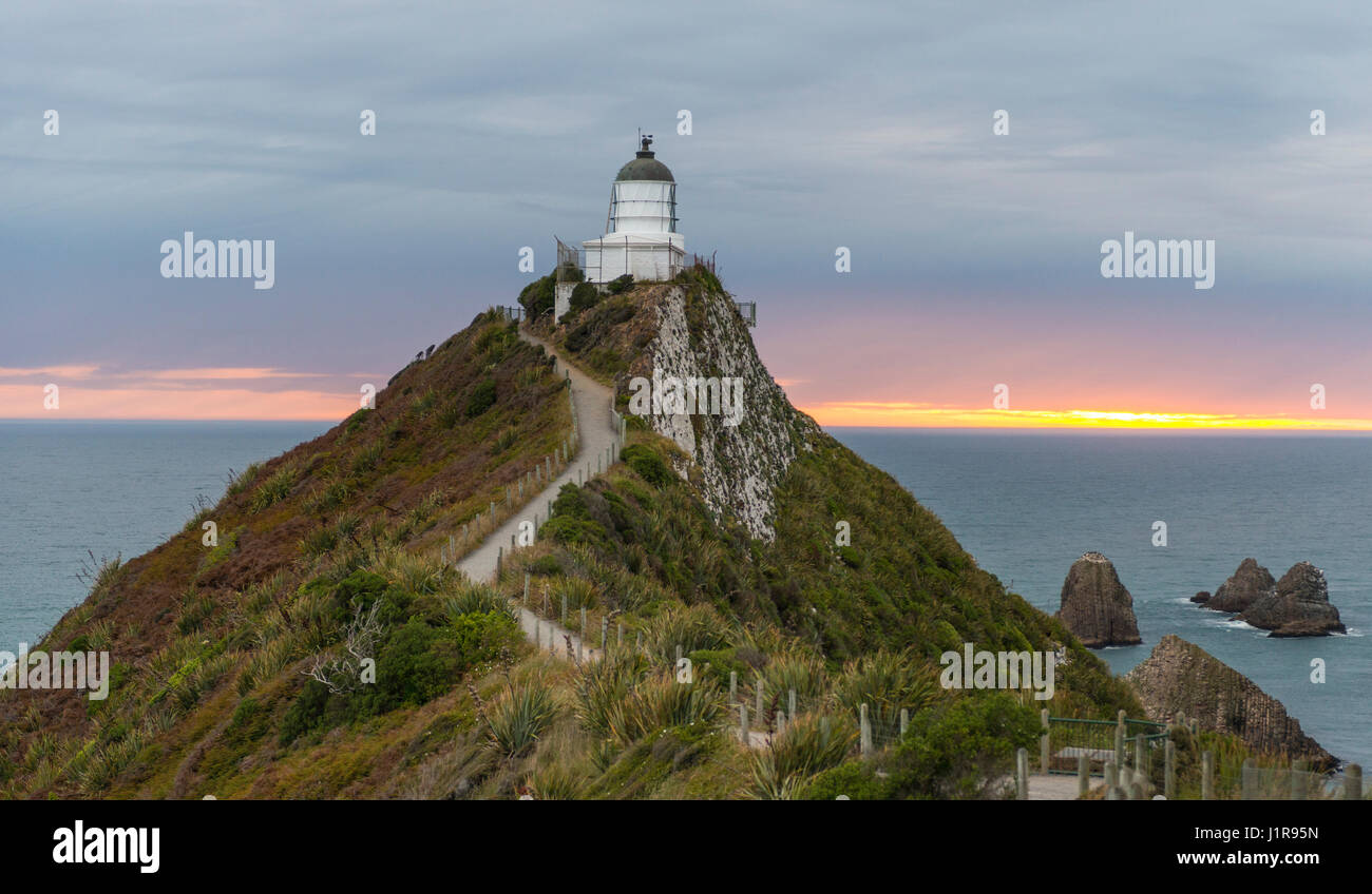 Le lever du soleil, au phare, le Nugget Point, Catlins, Région de l'Otago Southland, Nouvelle-Zélande Banque D'Images