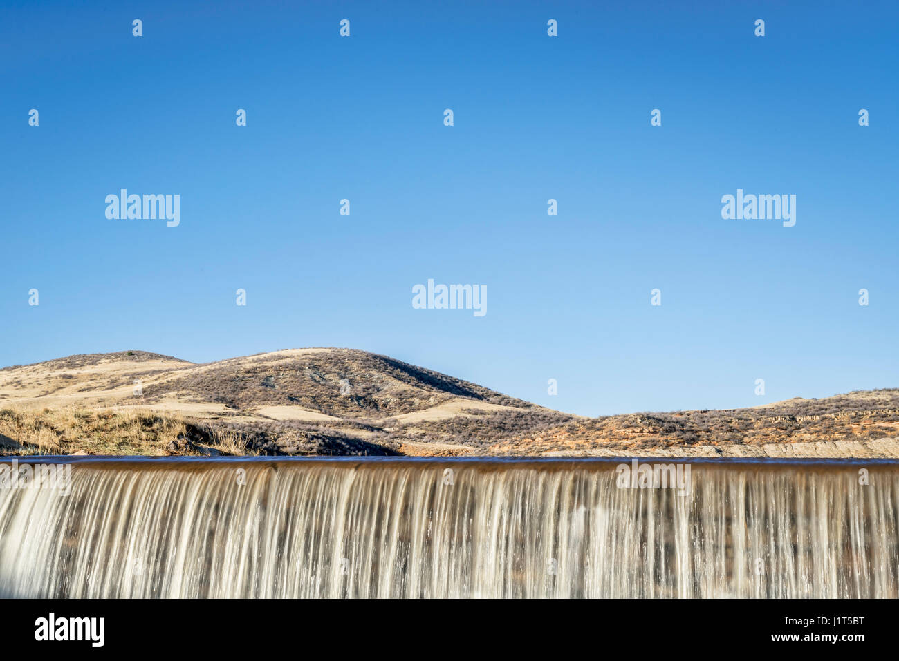 En cascade de l'eau sur un barrage à contreforts du Colorado contre le ciel bleu Banque D'Images