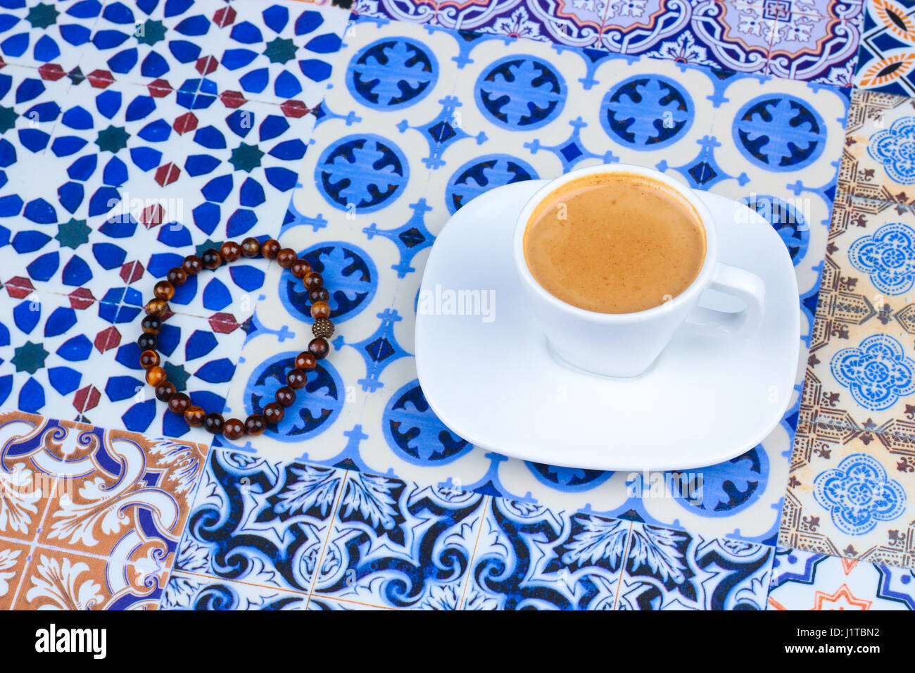 Tasse de café d'Arabie orientale sur un fond coloré / Espresso sur un fond coloré avec des fleurs, bagues et dates Tamr Banque D'Images