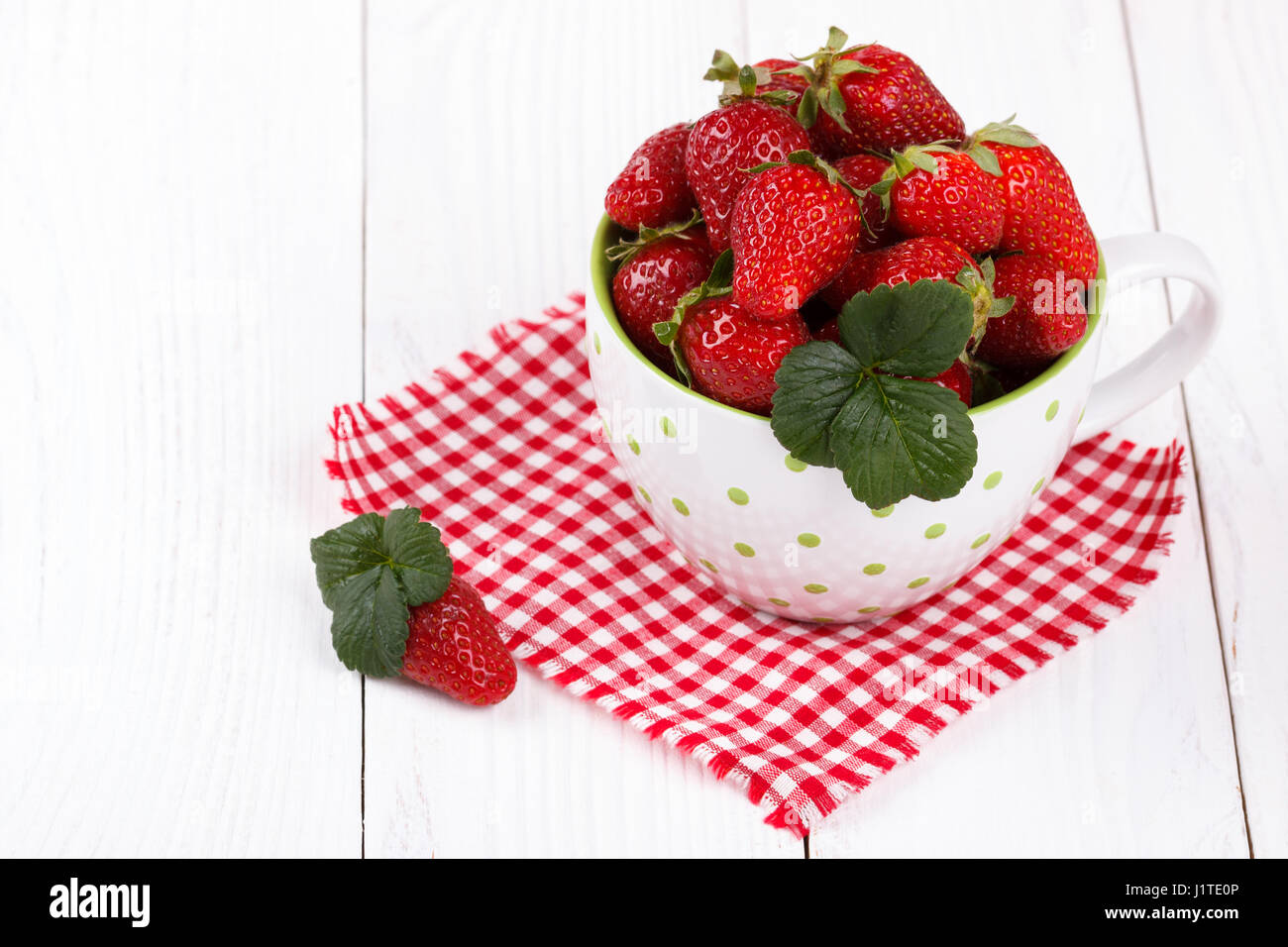 Rip frais fraises dans un bol sur la table en bois blanc Banque D'Images