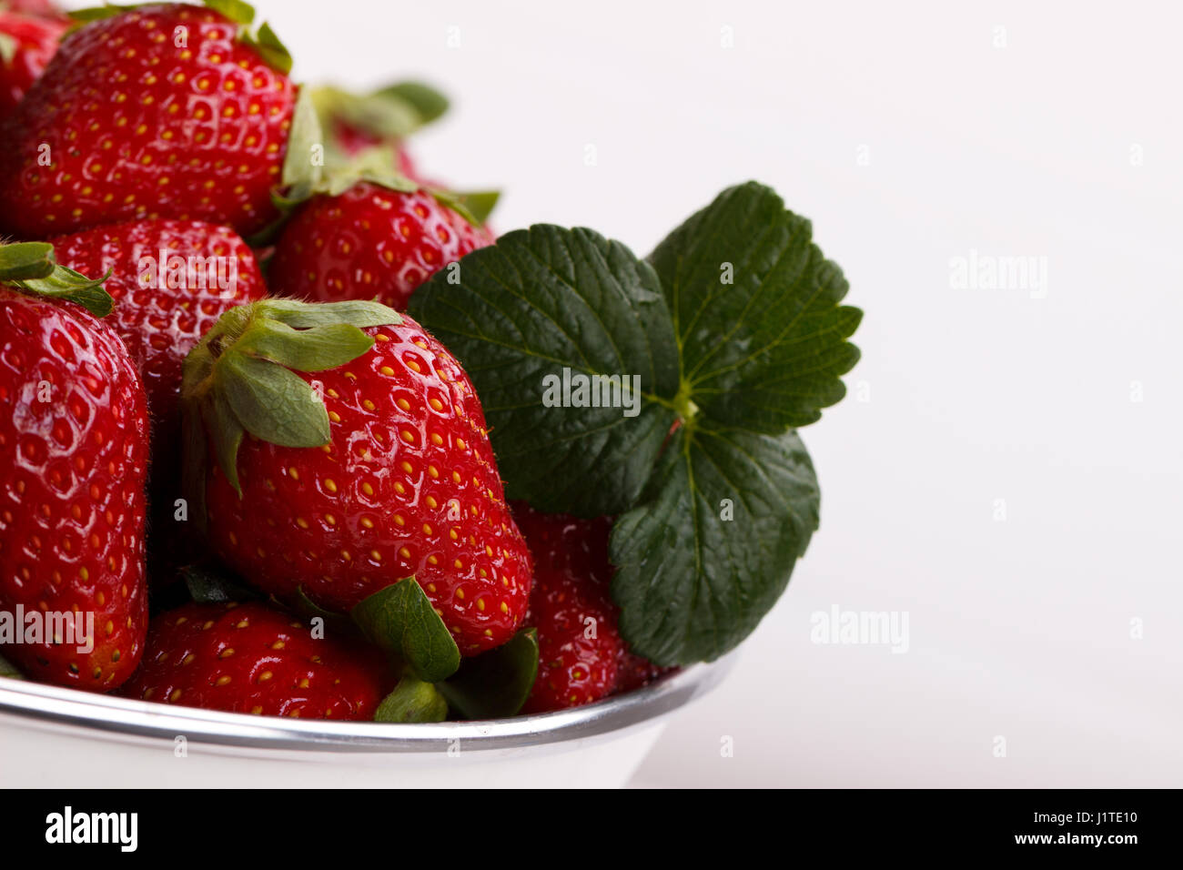 Rip frais fraises dans un bol sur la table en bois blanc Banque D'Images