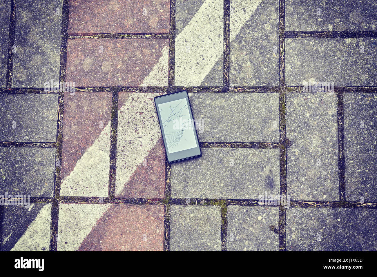 Téléphone mobile avec écran cassé sur une rue, harmonisation des couleurs appliquées, vue d'en haut. Banque D'Images