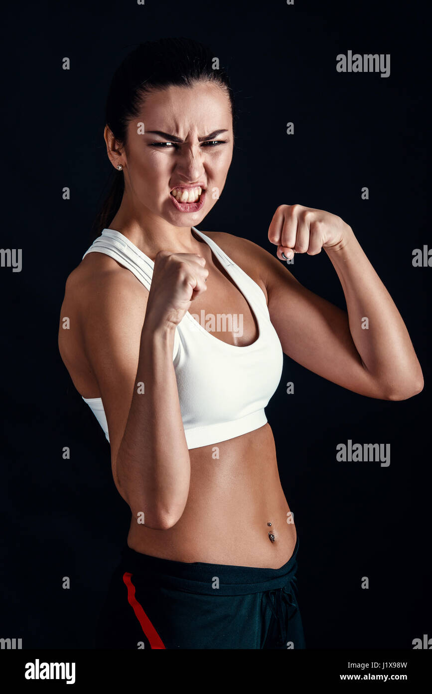 Fitness petite fille en colère prêt à combattre sur fond noir Banque D'Images