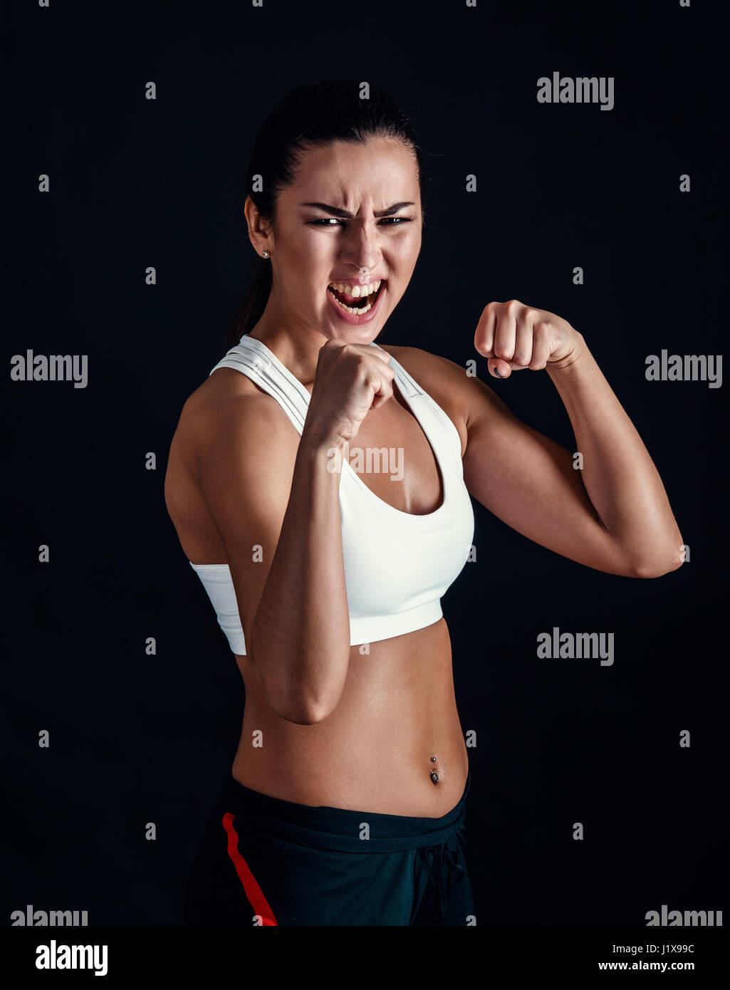Fitness petite fille en colère prêt à combattre sur fond noir Banque D'Images