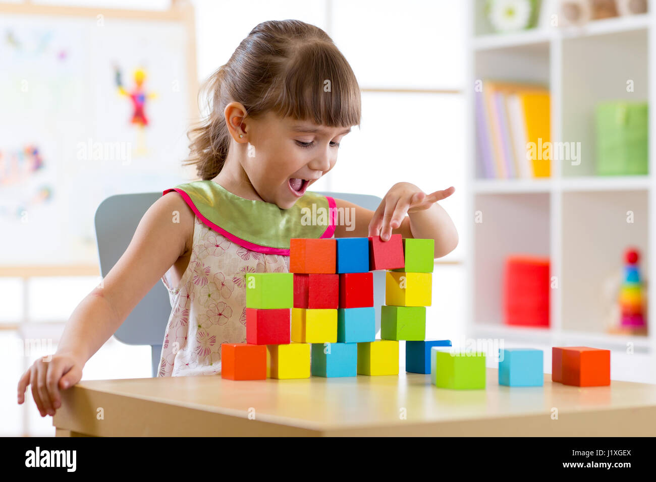 La petite fille jouant les jouets en bois à la maison ou au jardin Banque D'Images