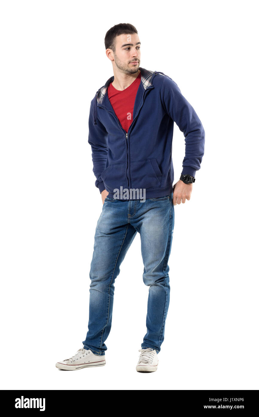 Jeune homme cool détendue en bleu sweat officiel avec les mains dans les poches arrière à l'arrière. La pleine longueur du corps portrait studio isolated over white background. Banque D'Images
