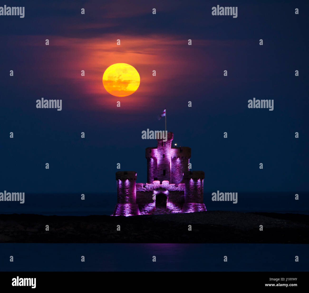 Sang rouge lune croissante au tour de refuge sur l'île de Man. Tower est éclairé avec lueur violette. Banque D'Images