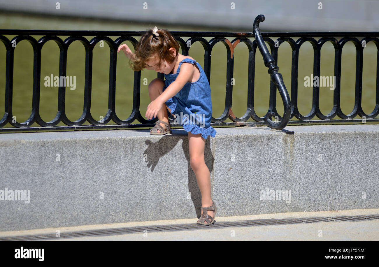 Une petite fille de descendre une clôture. Parque del Retiro, Madrid, Espagne Banque D'Images