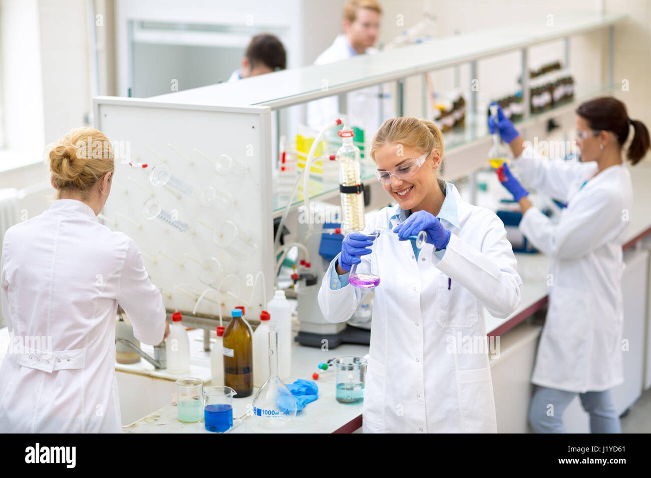 Jeune chimiste verser le liquide dans une fiole chimique in lab Banque D'Images