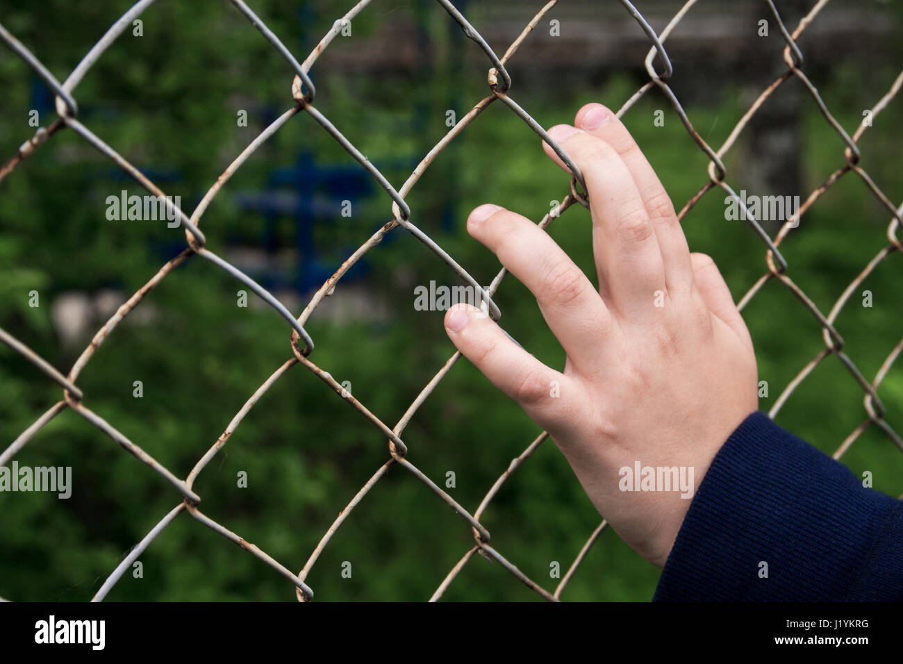 La main avec cage en treillis métallique. Les mains de l'enfant avec grillage de séparation en acier. Banque D'Images