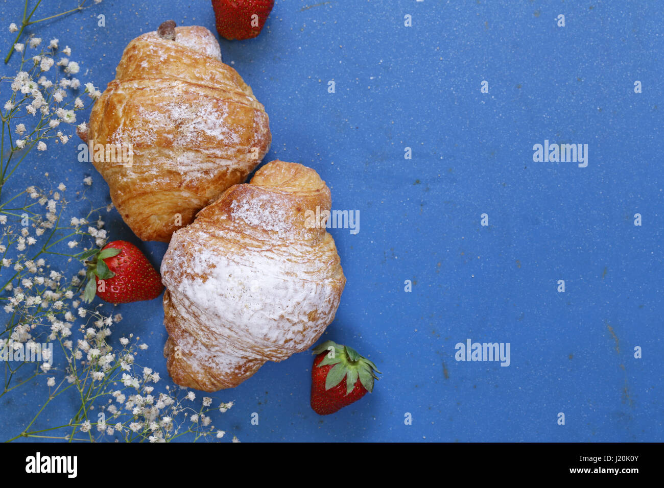 Les croissants avec du sucre en poudre et les fraises Banque D'Images