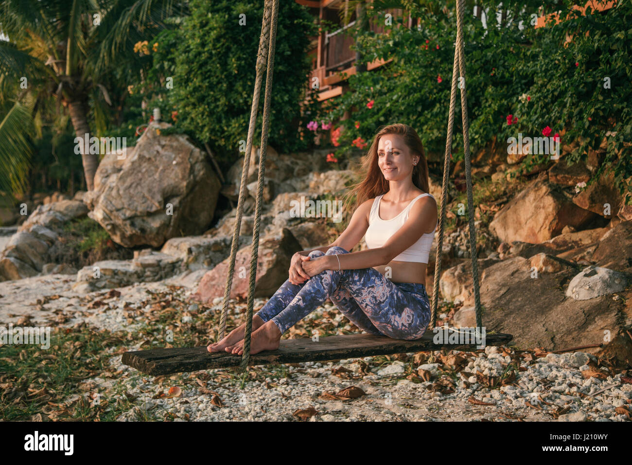 Femme assise sur une balançoire à la plage Banque D'Images