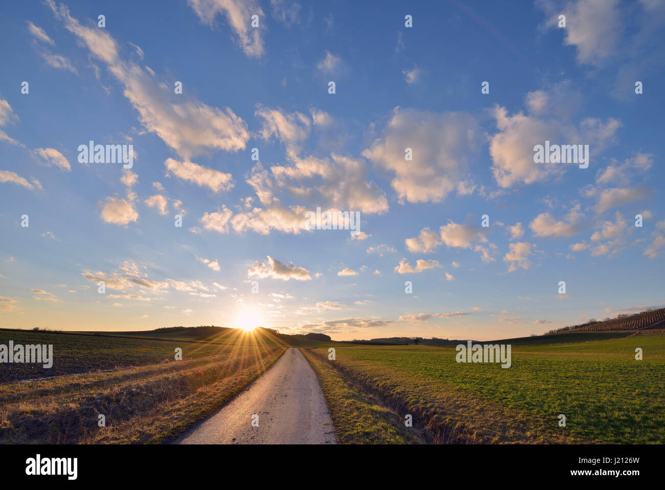 Coucher du soleil avec petit chemin rural à travers champs, l'hiver. La Bavière, Allemagne. Banque D'Images