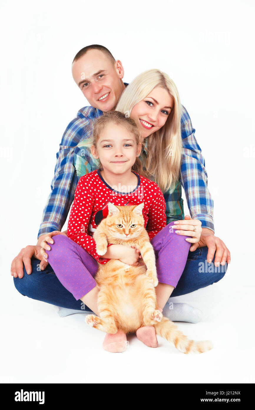 Famille heureuse et un chat assis en studio sur un fond blanc. Banque D'Images