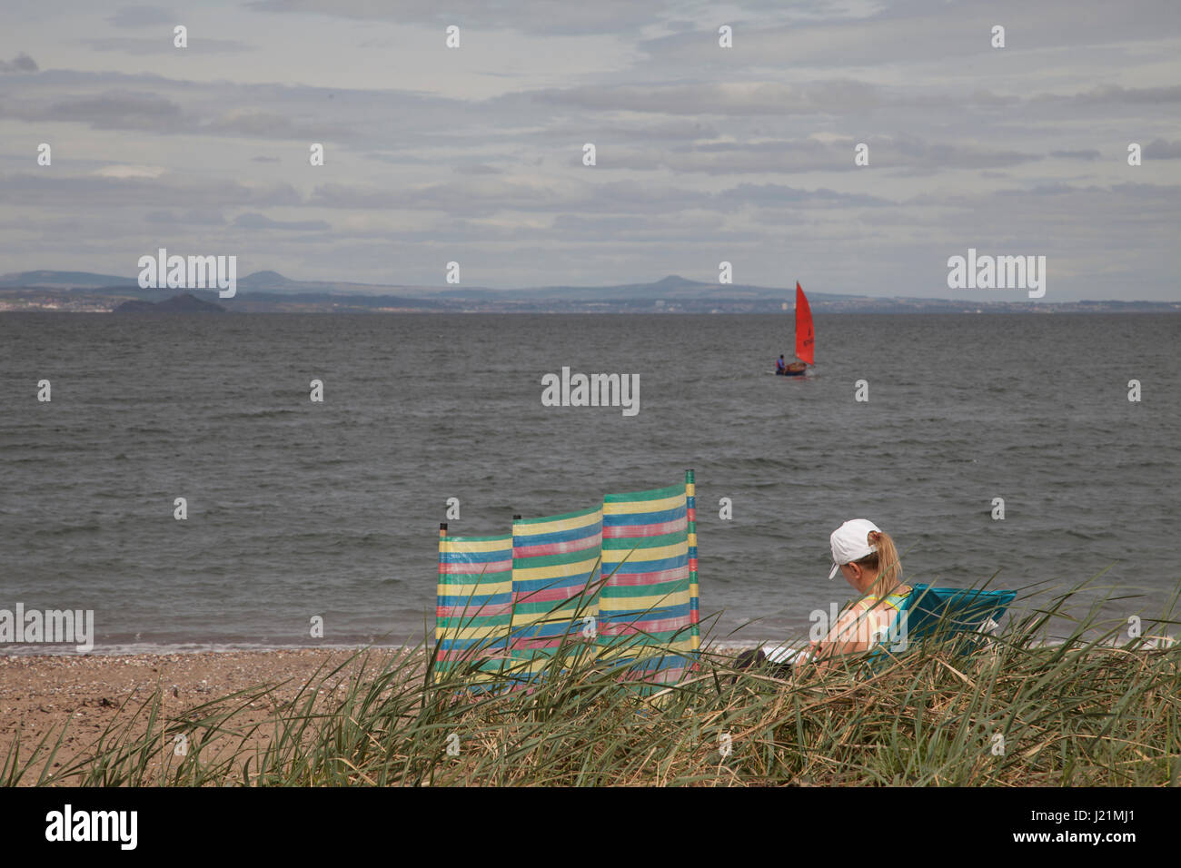 Edinburgh, Ecosse, Royaume-Uni. Apr 23, 2017. Femme en train de bronzer sur la journée ensoleillée à Musselburgh beach, Édimbourg, Écosse, Royaume-Uni. L'homme de la voile sur la mer ouverte. Météo : 23 avril 2017 : nuageux avec éclaircies. Crédit : Gabriela Antosova/Alamy Live News Banque D'Images