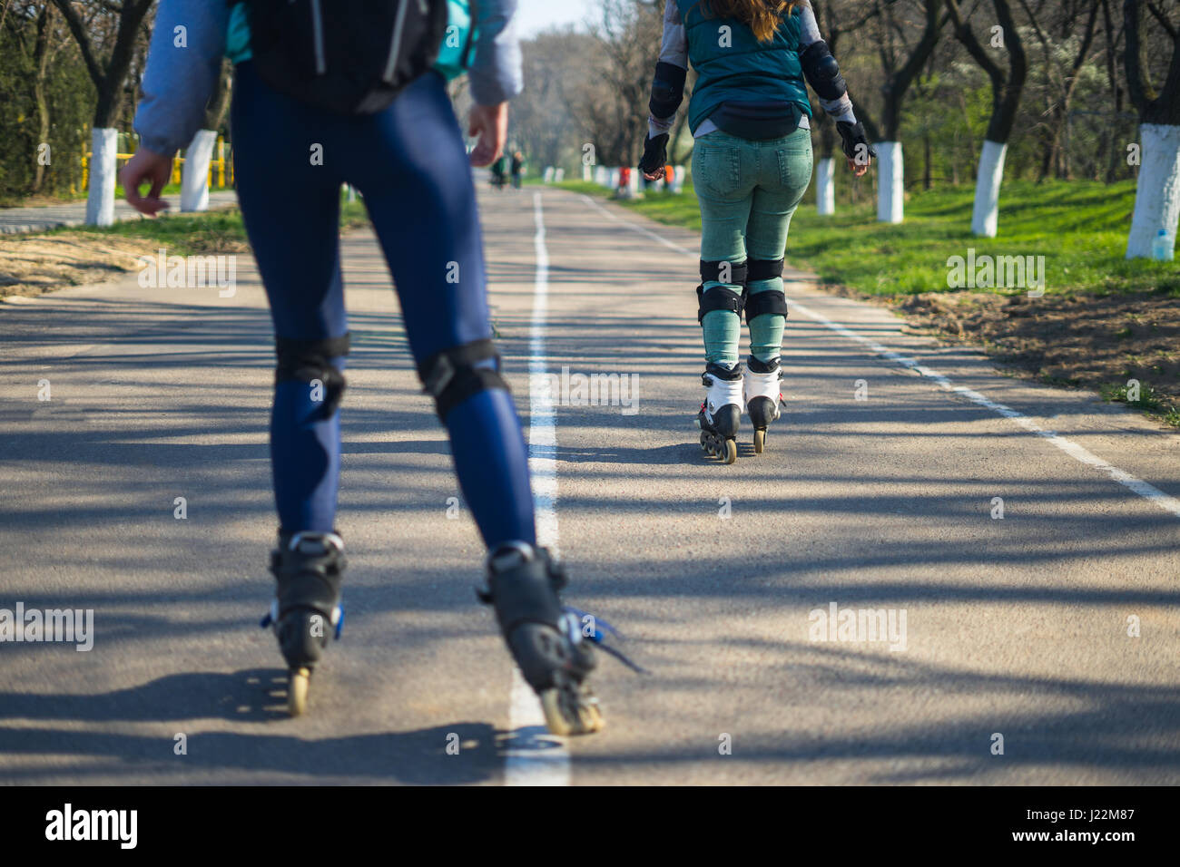 Deux filles sur patins à rouler le long de la route à côté de l'autre Banque D'Images