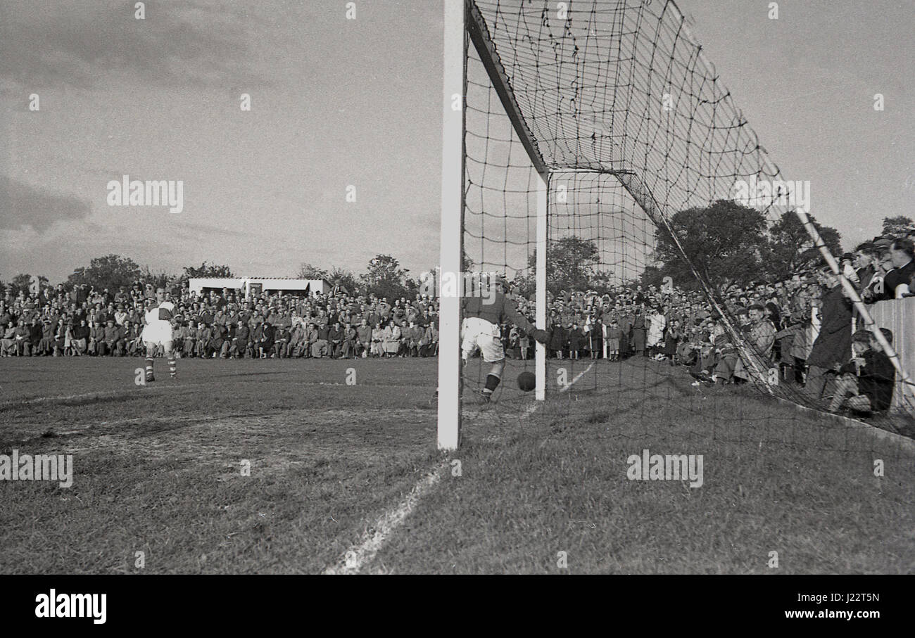 1950, en Angleterre, un match de football à Aylesbury United F.C, un club amateur formé en 1897. Gardien de but dans son objectif permet de s'assurer que le ballon va au-delà du portique. Banque D'Images