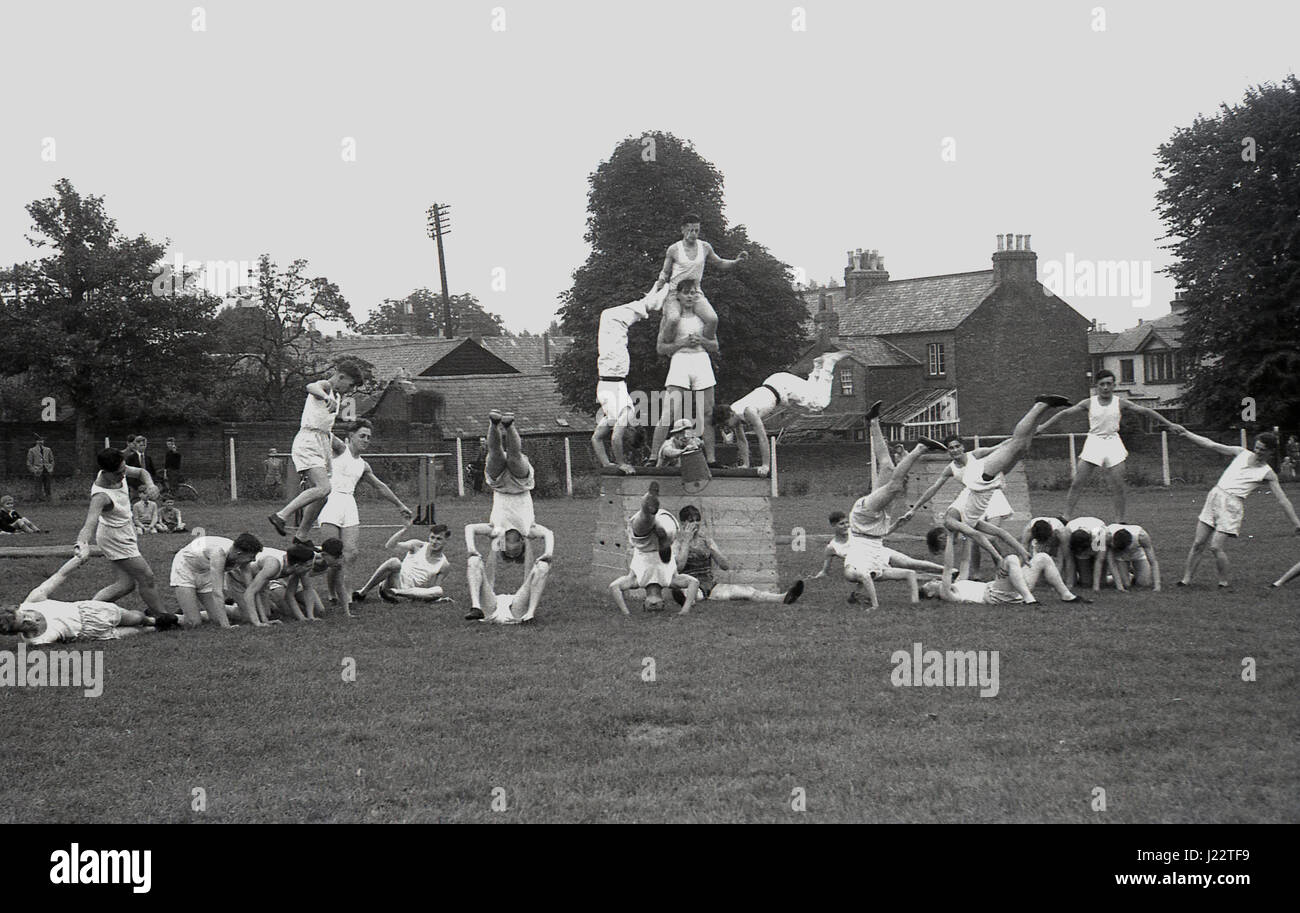 1950, groupe de gymnastes masculins de faire un affichage de compétences en dehors de gymnastique dans un champ. Banque D'Images
