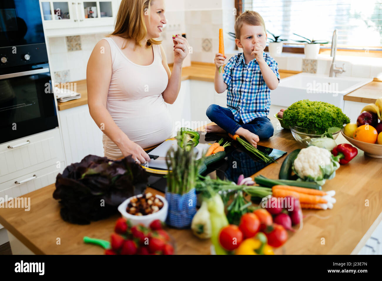 Maman enceinte et l'enfant la préparation de repas et ingrédients de dégustation Banque D'Images