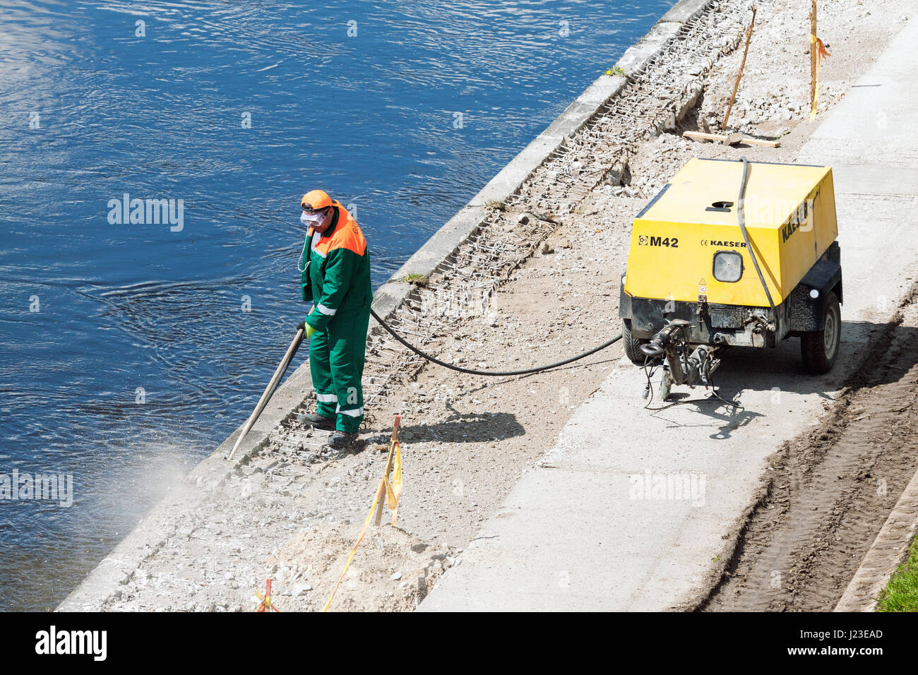 VILNIUS, LITUANIE - 02 MAI 2016 : ouvrier de construction en béton nettoyage avec l'aide de compresseur industriel au bord de la rivière à Vilnius Banque D'Images