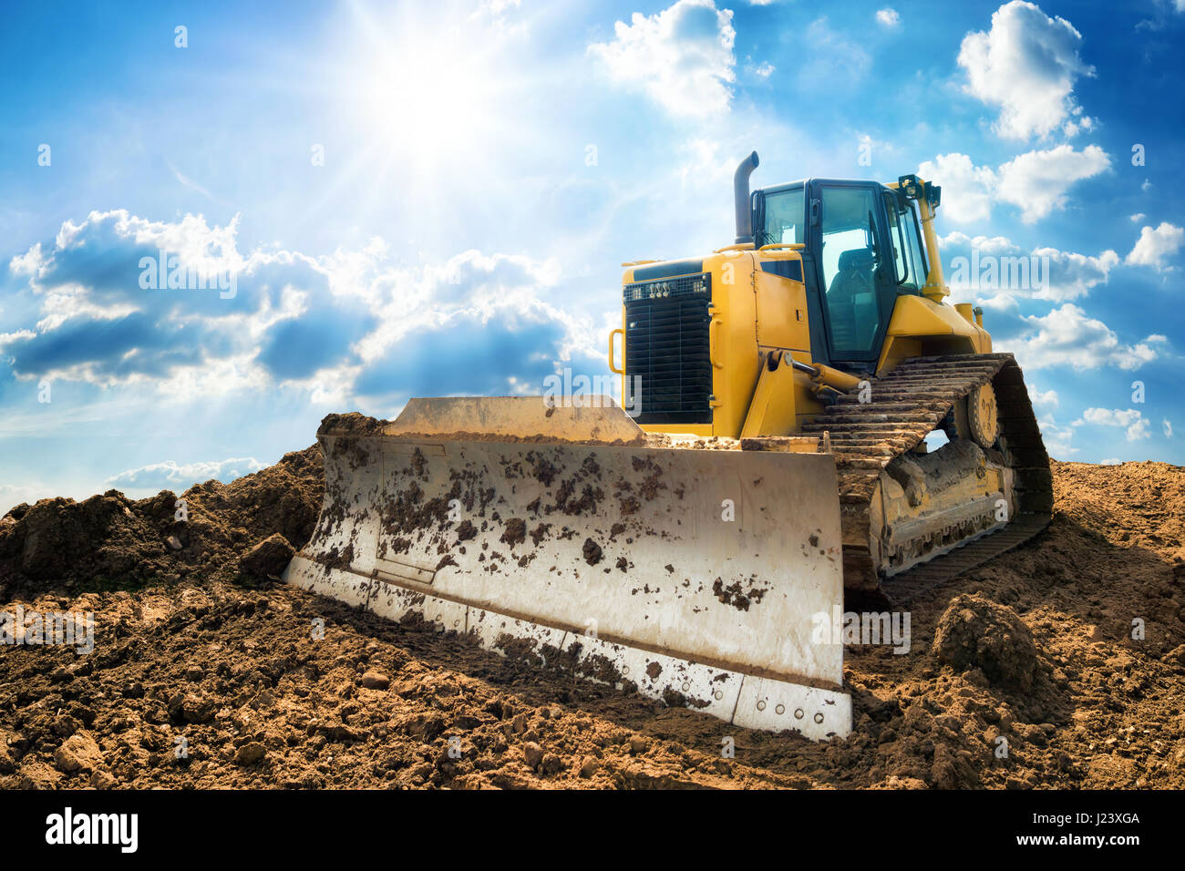 Excavatrice jaune sur la construction de nouveaux site, avec le soleil clair et beau ciel bleu en arrière-plan Banque D'Images