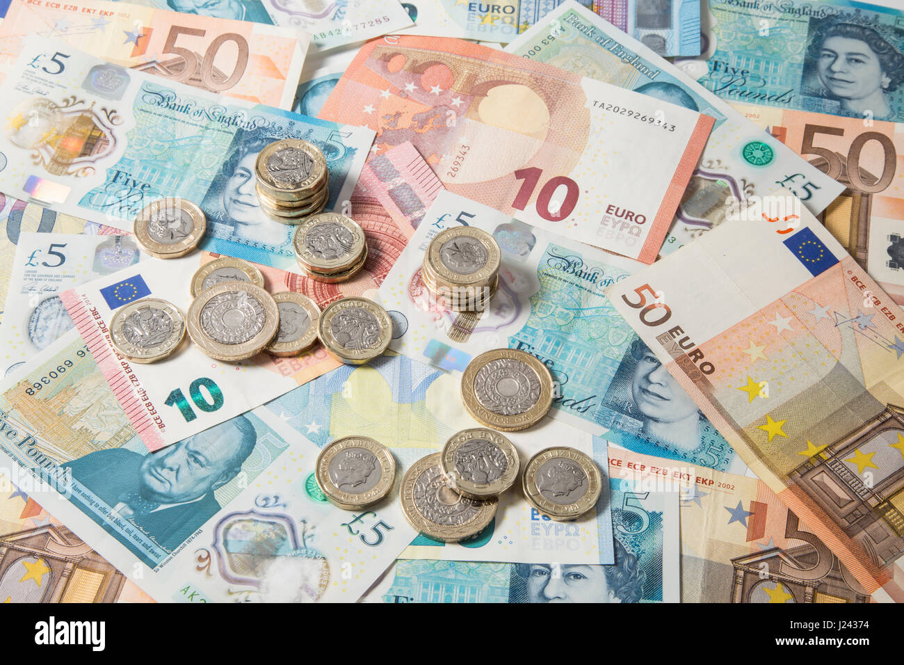 New British £1 et £2 pièces sur un fond d'Euros et £5 pound note Banque D'Images