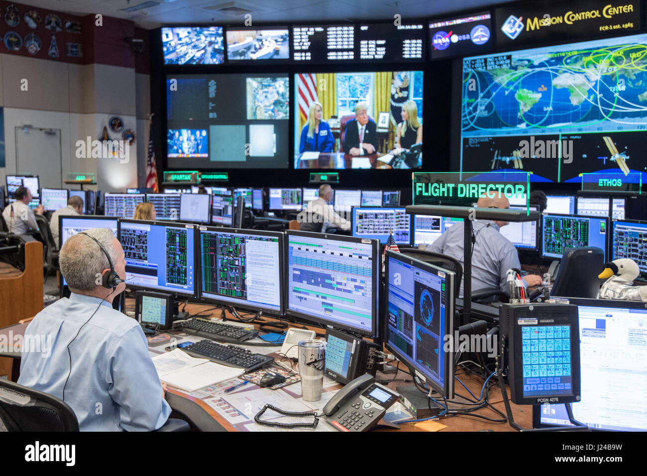 Le directeur de vol de la NASA Brian Smith, gauche, contrôle l'activité au  centre de contrôle de mission en tant que président, Donald Trump parle  avec les astronautes de la NASA Peggy