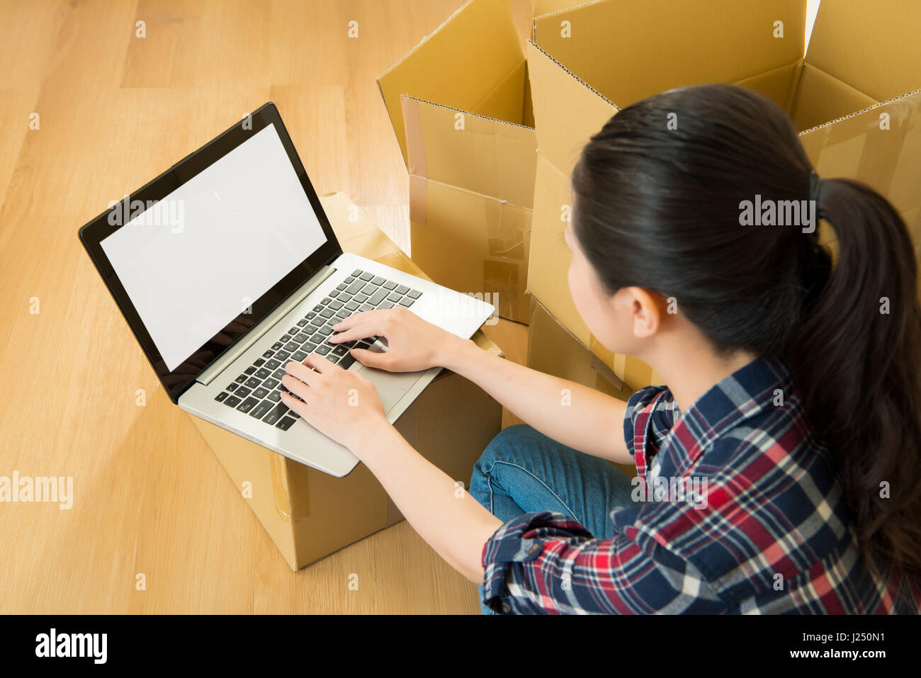 Jeune femme déménagement dans un nouvel appartement, assis sur le plancher et de naviguer sur le web sur un ordinateur tablette à la recherche de nouvelles idées de décoration. mixed race asian ch Banque D'Images