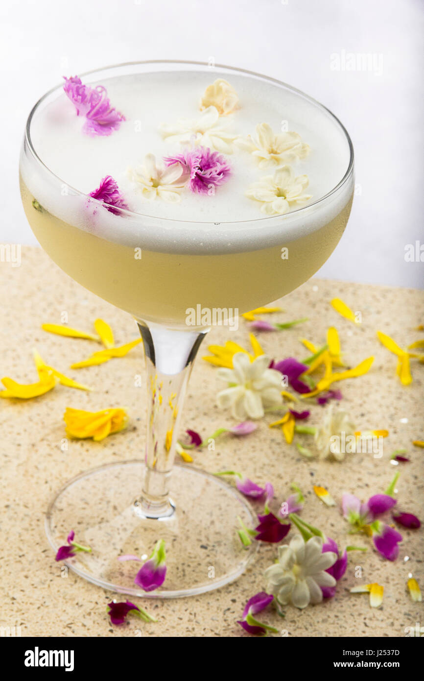 Gin, thé au jasmin, citron, Cointreau, sirop de blanc d'oeuf dans un coupétte et garni de fleurs comestibles et de jasmin Banque D'Images