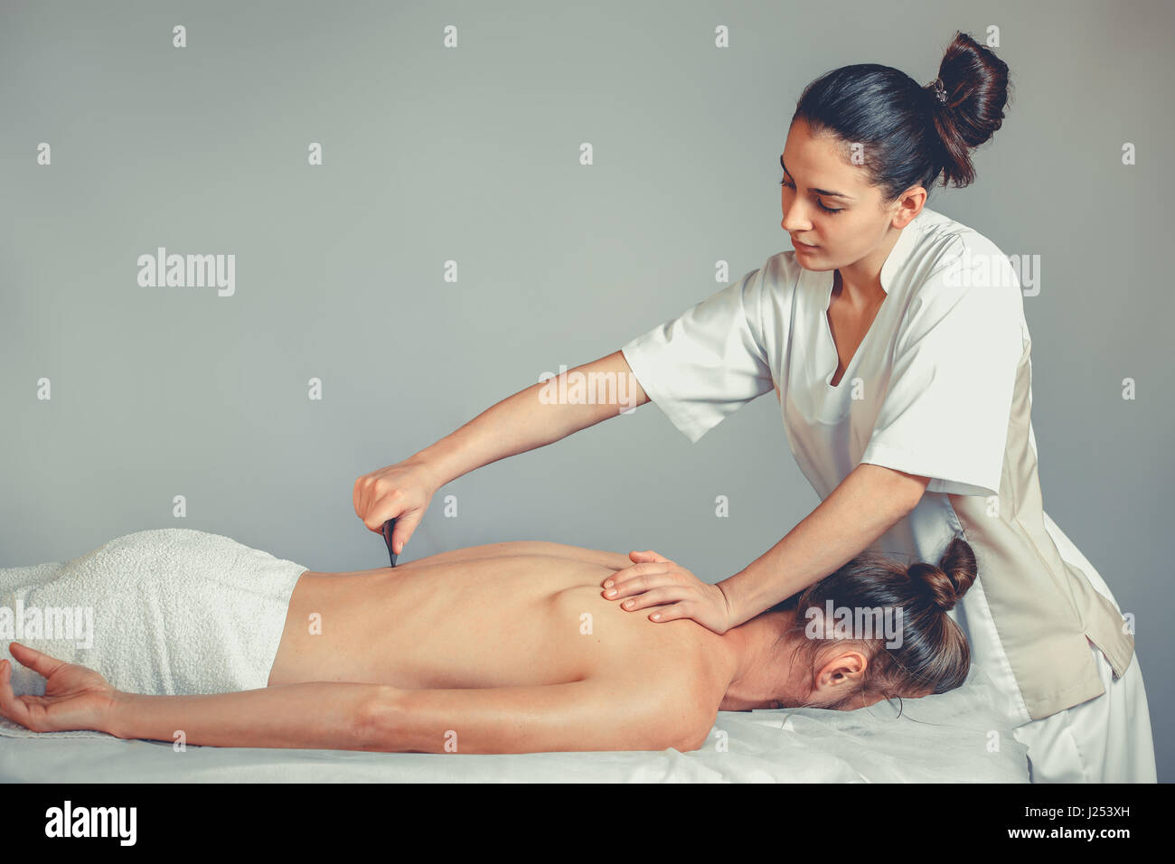 Gua Sha, Massage Therapy. Une jeune femme professionnelle rend masseur massage Thaï. Le patient est allongé sur un lit et est recouvert d'une serviette blanche. Trea Banque D'Images