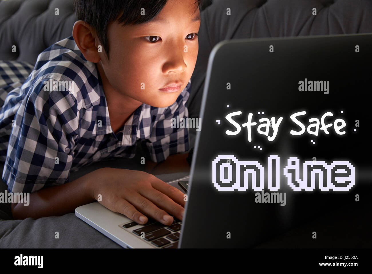 Garçon à la maison en utilisant un ordinateur portable avec Internet en toute sécurité un Message Banque D'Images