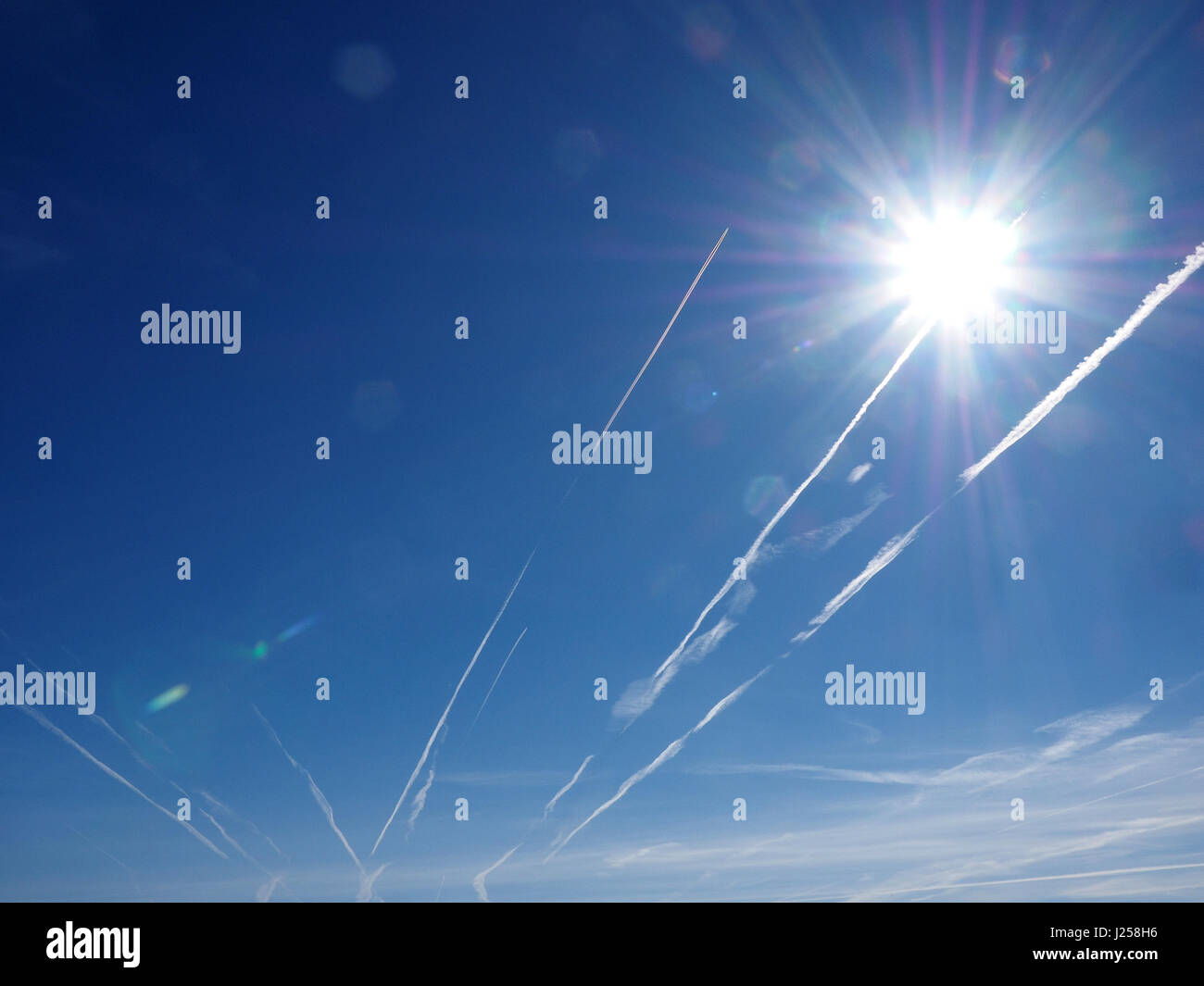 Non-diffusion de trainées d'avions dans le ciel bleu au-dessus de Cumbria England UK avec reflets spéculaires de starburst & sun frais généraux Banque D'Images