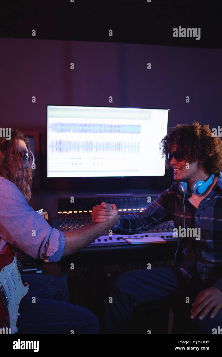 Les ingénieurs audio mâle shaking hands in recording studio Banque D'Images