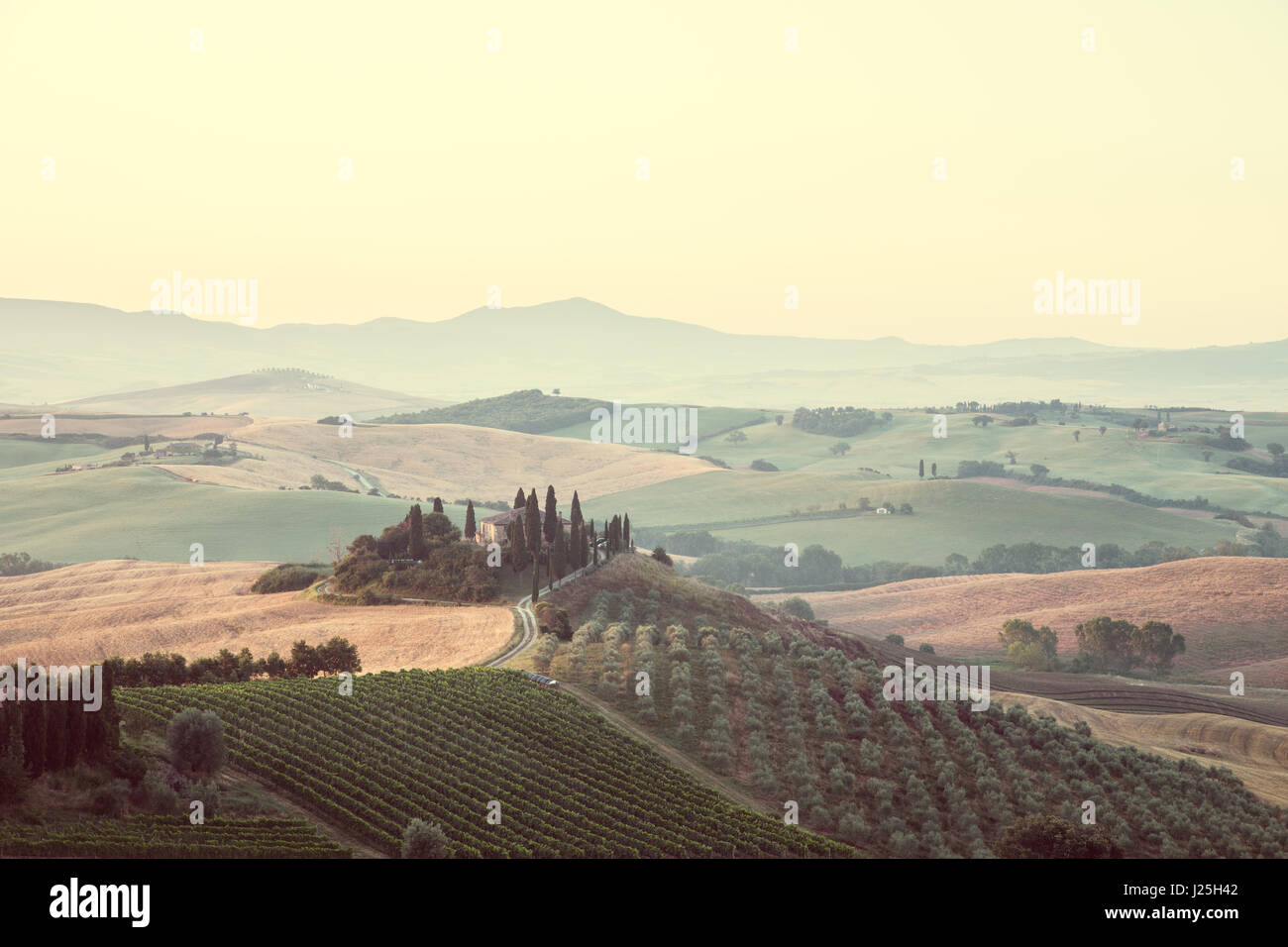 La vue classique du paysage pittoresque de la Toscane avec célèbre ferme au milieu de collines et de vallées idylliques dans la belle lumière du matin au lever du soleil d'or Banque D'Images