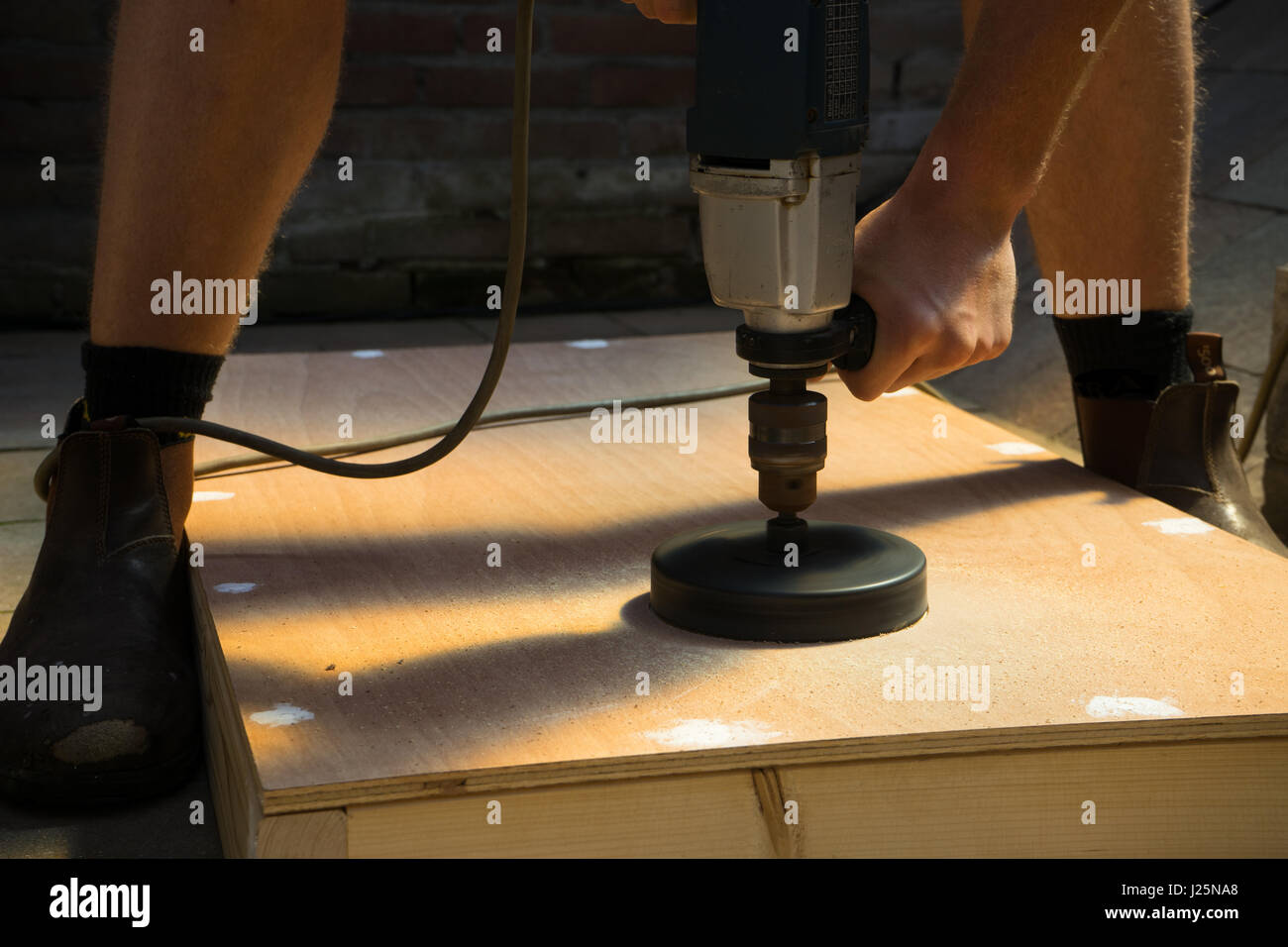 L'homme scie avec trou de coupe sur bois conseil cornhole projet de bricolage Banque D'Images