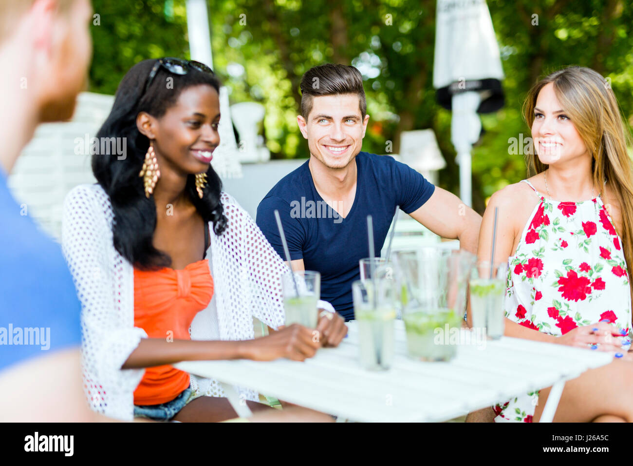 Les jeunes et happy friends sitting parle à une table à l'extérieur et smiling Banque D'Images
