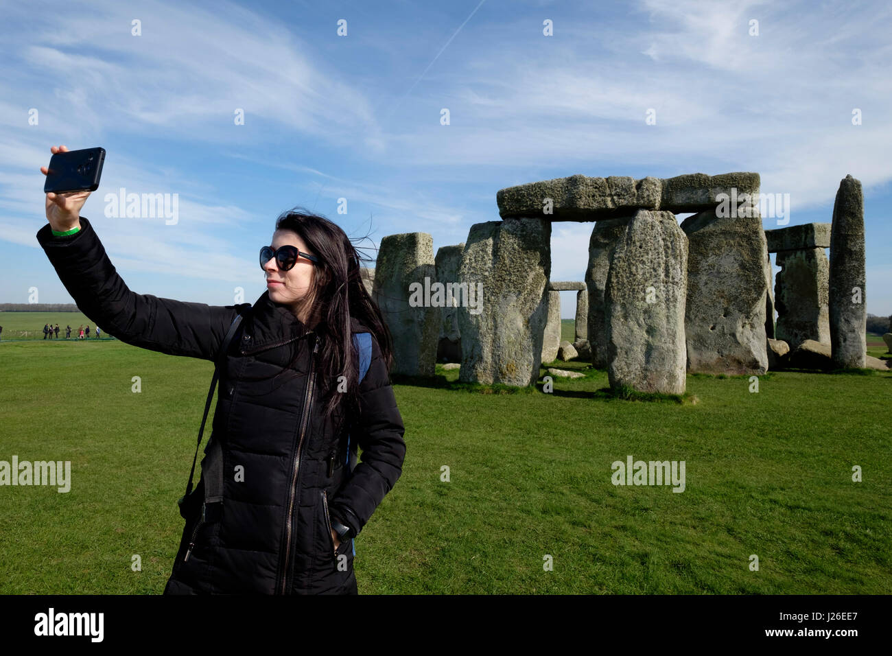 Jeune femme tenant un avec leur smartphone selfies en face du monument préhistorique de Stonehenge dans le Wiltshire, Angleterre Banque D'Images