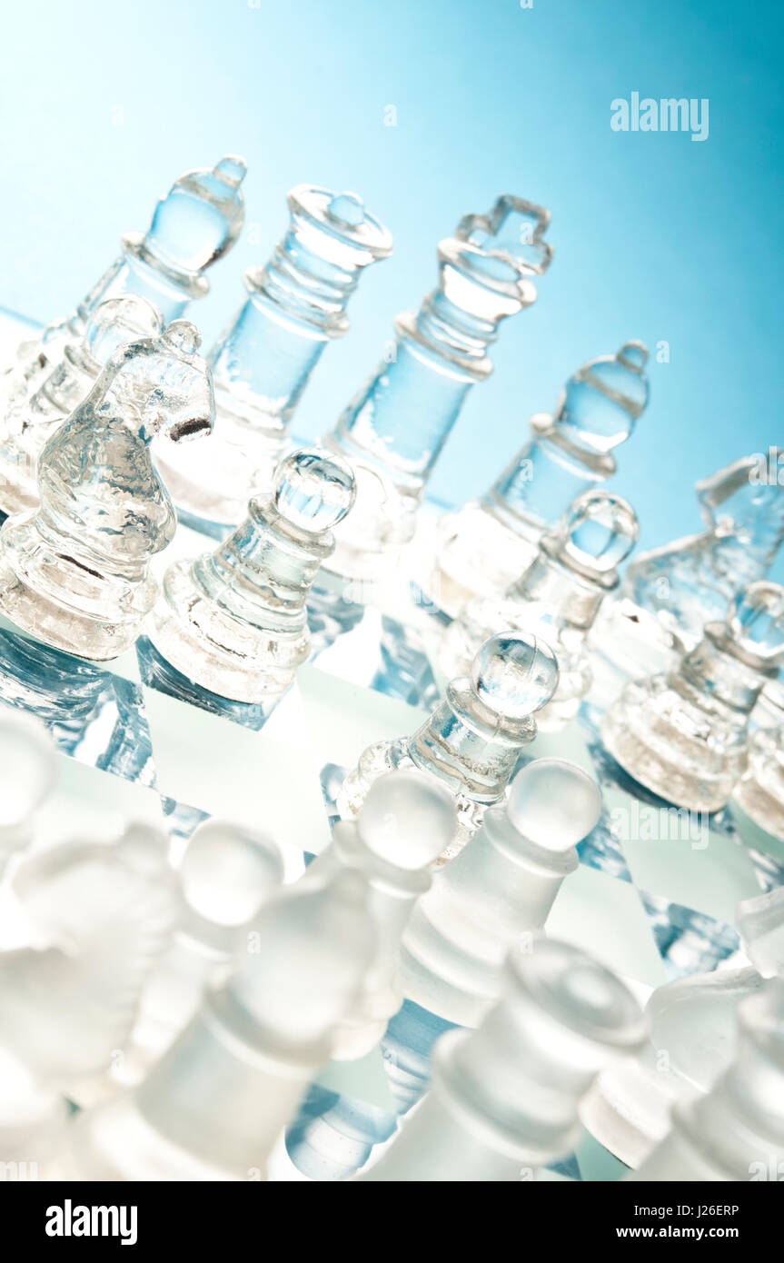 Gros plan de pièces d'échecs en verre mat et transparent sur un échiquier en verre bleu, vu de dessus sous un angle diagonal Banque D'Images