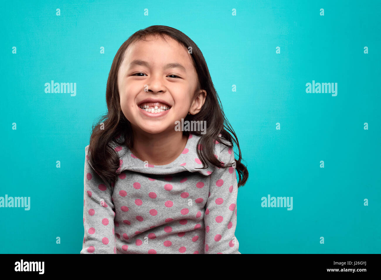 Smiling asian petite fille et ses dents cassées sur fond bleu Banque D'Images