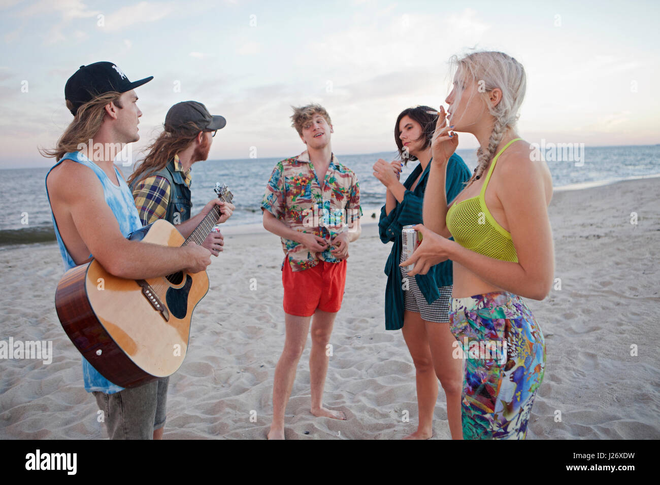 Amis jouant de la musique ensemble sur une plage Banque D'Images