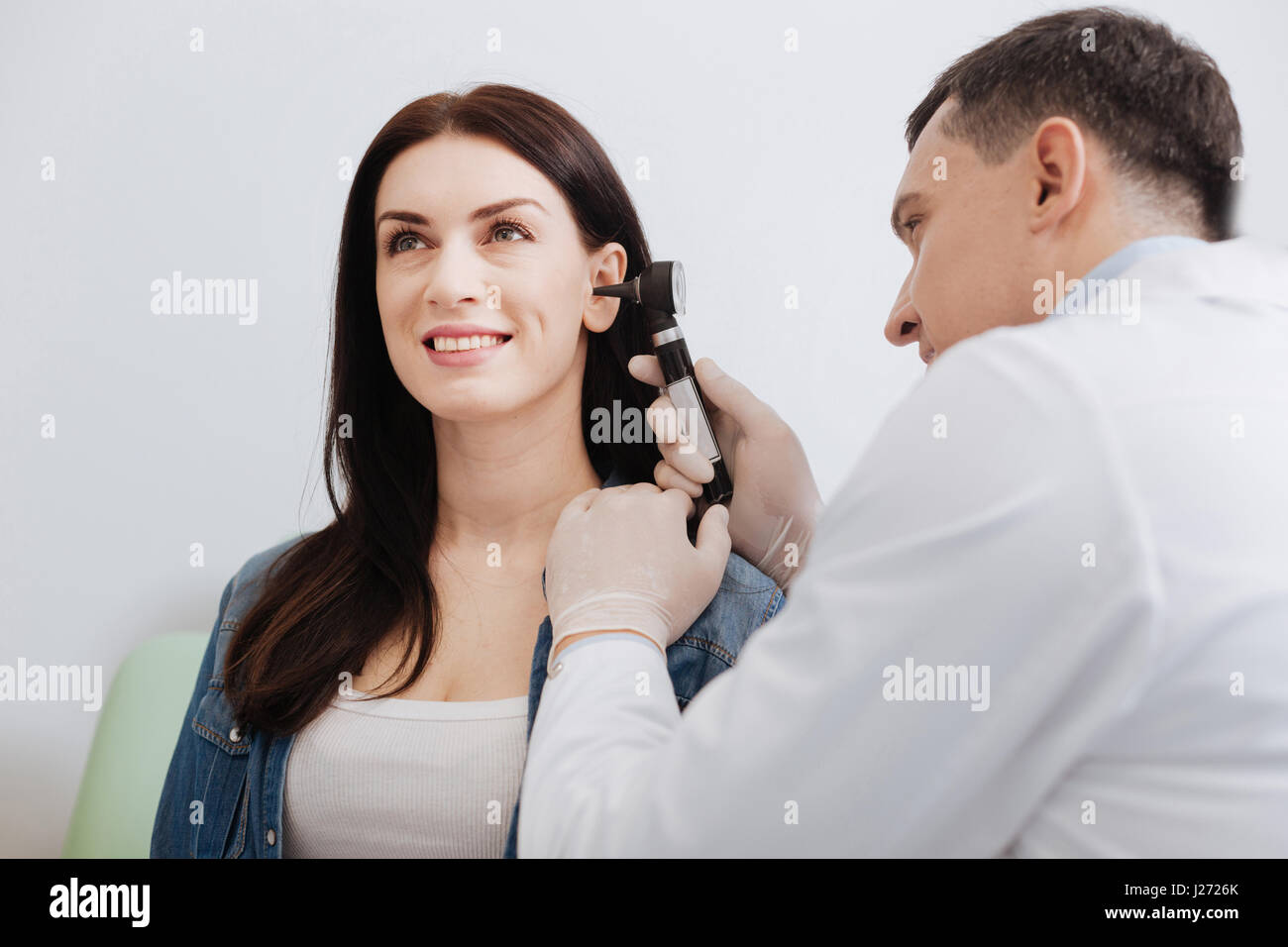 Médecin attentif examen de l'oreille faisant de jolie femme Banque D'Images