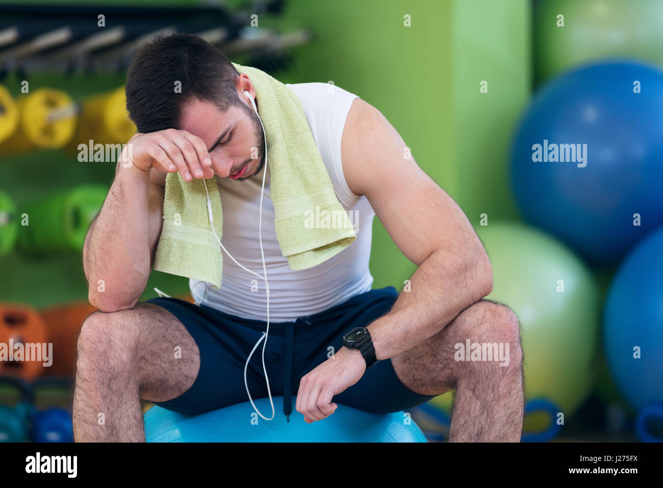 Athlète masculin à genoux par les haltères toweling sueur de son front. Banque D'Images