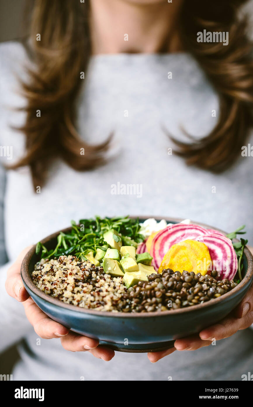 Une femme portant une chemise grise est maintenant une abondance bol composé de quinoa, les germes, les lentilles, les avocats, et de Chioggia betterave. Banque D'Images