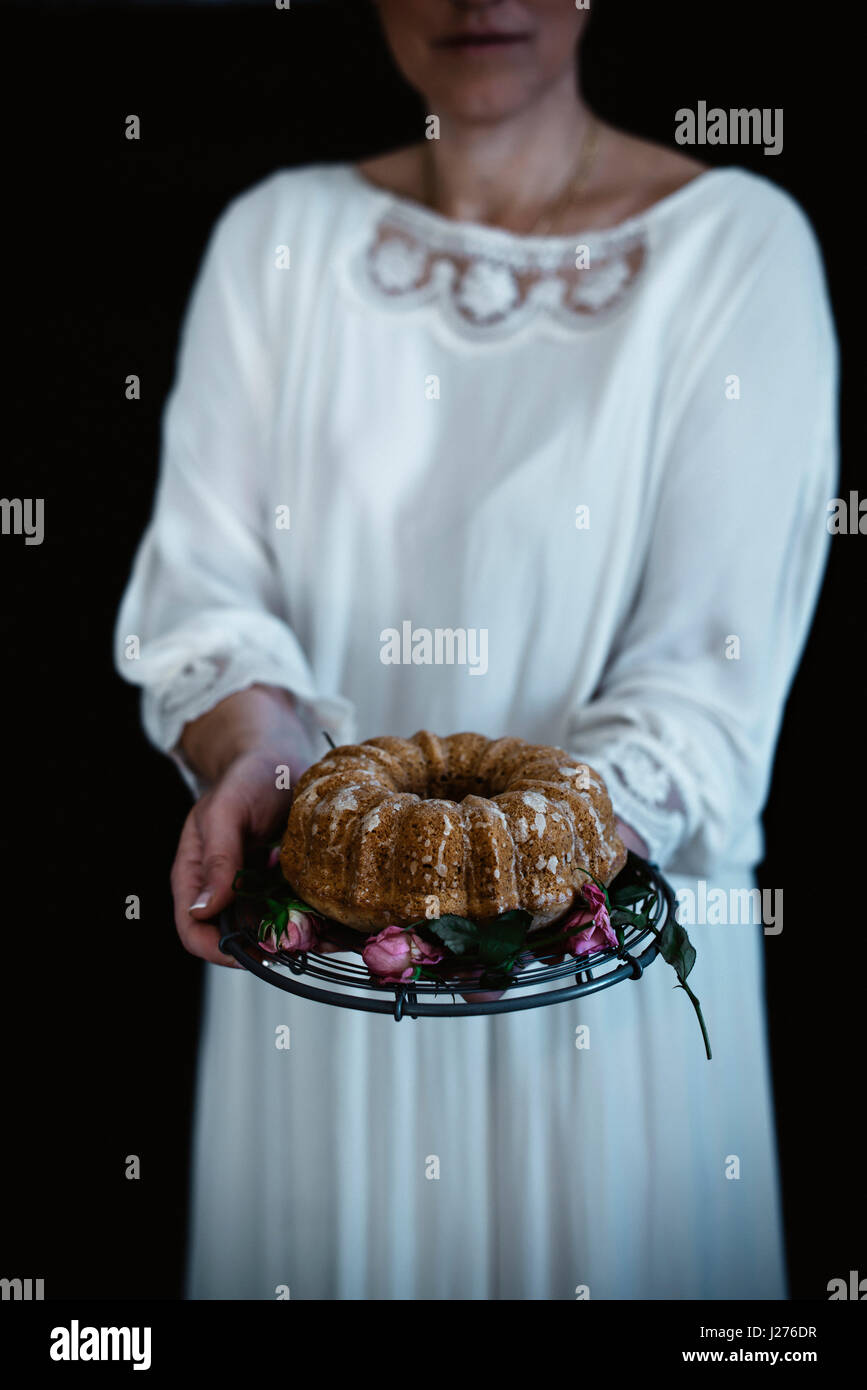 Une femme tenant un gâteau poire sur un cake stand. Banque D'Images