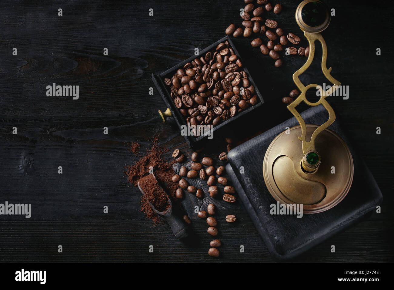 Les grains de café torréfiés et moudre le café dans la boîte en bois avec vintage coffee grinder et scoop sur fond gravé en bois noir. Vue de dessus avec l'espace. Banque D'Images
