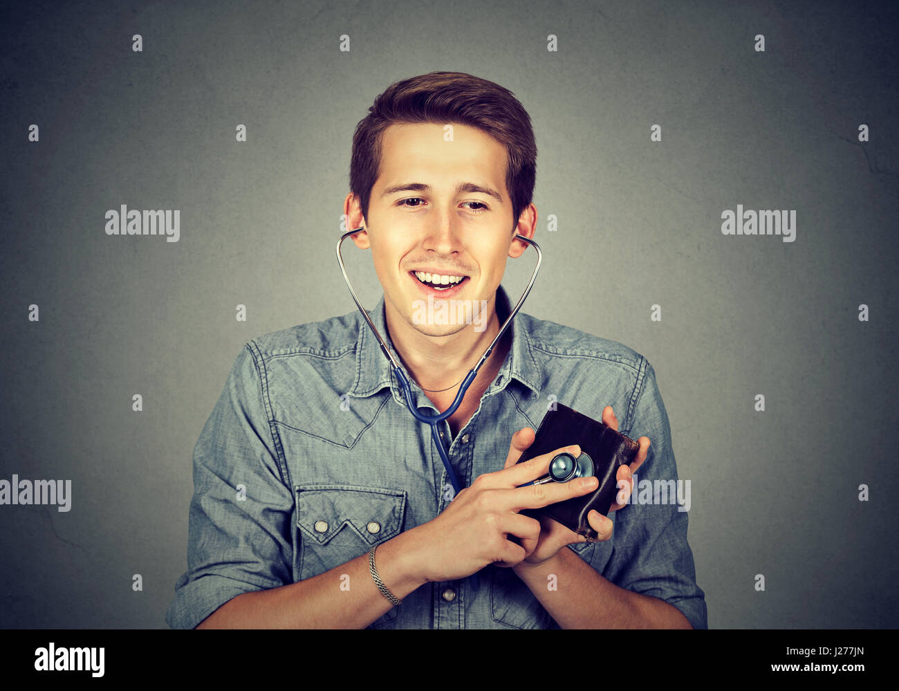 Jeune homme contrôle de portefeuille avec stéthoscope. Notion de réussite financière. Banque D'Images