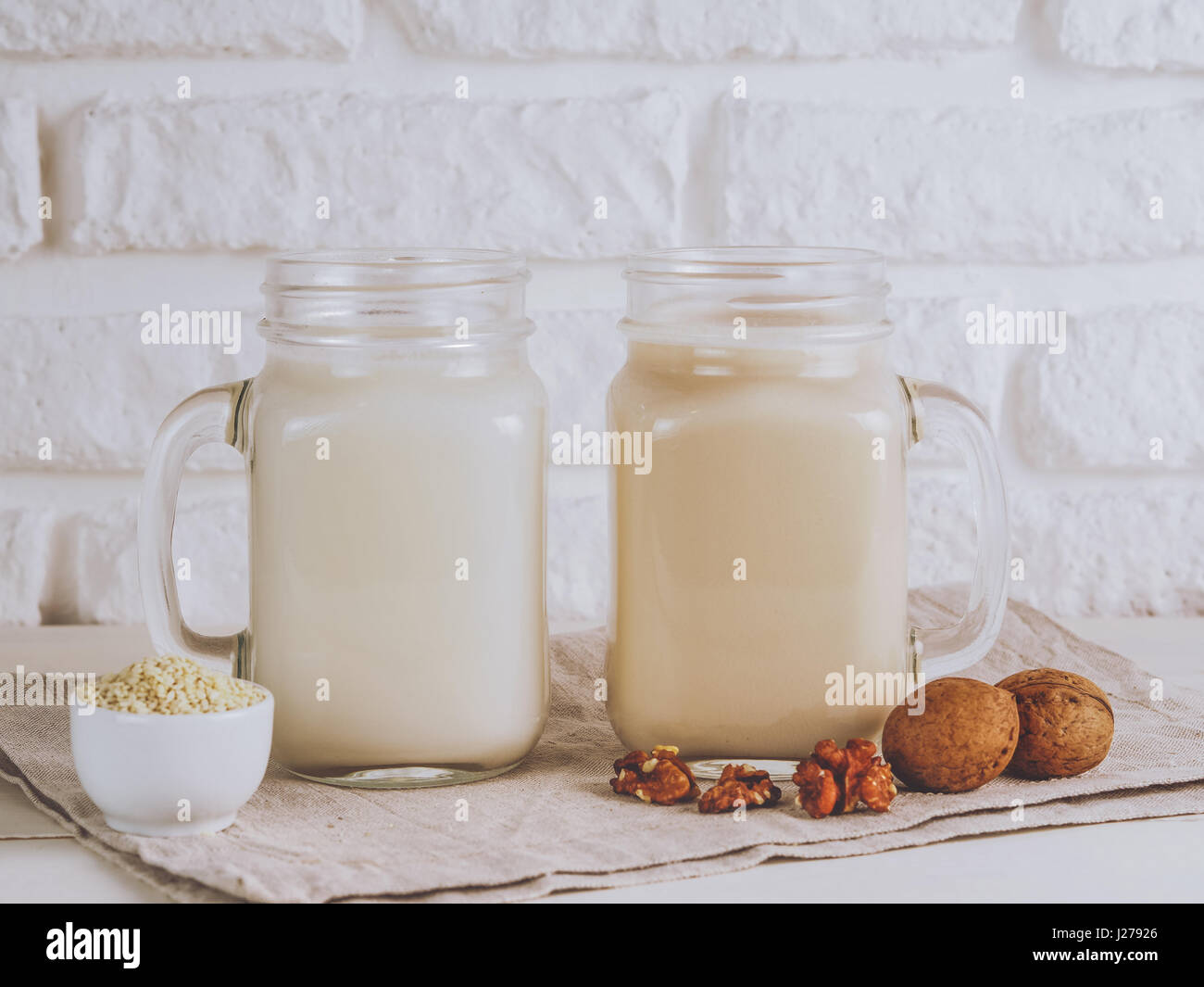 Plan rapproché sur deux pot Mason vegan avec du lait de noix et graines de sésame sur le tableau blanc. Copier l'espace. Banque D'Images